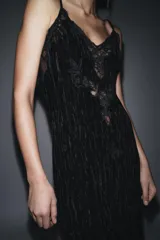 Vestido midi de estilo lencero confeccionado en terciopelo negro, con escote en pico, tirantes finos ajustables y detalles de encaje a tono en el escote y el bajo.