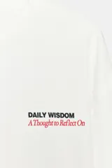 Camiseta de manga larga color blanco, corte regular fit, con cuello redondo y bajo recto. Presenta un pequeño texto estampado en color rojo en el pecho.