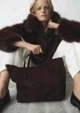 Bolso tipo shopper de piel de serraje color marrón oscuro, con doble asa de hombro y cierre de botón magnético. Incluye forro interior de algodón y bolsillo con cremallera.