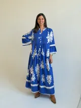 Vestido largo color azul con estampado ornamental en color blanco, escote en V con botones frontales y mangas tres cuartos con volados.