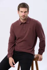 Remera polo de manga larga confeccionada en tejido jersey, con cuello clásico y cierre frontal de tres botones. Presenta un diseño liso con un pequeño logo bordado en el pecho y una etiqueta decorativa en el ruedo.