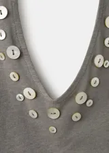 Top gris de corte entallado y escote halter, sin mangas, confeccionado en mezcla de lino y algodón. Presenta un diseño adornado con botones decorativos de nácar a lo largo del escote y los tirantes.