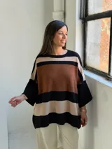 Poncho de tejido de punto con diseño de rayas horizontales anchas en tonos negro, marrón y beige, con cuello redondo y mangas amplias.