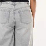 Jean de corte wide leg y talle alto, color gris lavado, con costuras verticales decorativas en el frente y ruedo ancho.