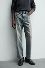 Jeans de corte recto y tiro medio confeccionados en denim de algodón con efecto lavado, diseño de cinco bolsillos y cierre frontal con cremallera y botón.