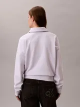 Buzo Calvin Klein de tejido french terry color lila claro, con cuello tipo polo y cierre de media cremallera. Cuenta con el logo de la marca bordado en el pecho y diseño de manga larga.