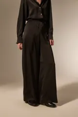 Pantalon de vestir de corte ancho y tiro alto, confeccionado en tela de viscosa con acabado satinado. Presenta cintura elástica y diseño fluido.