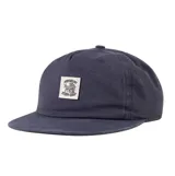 Gorra de visera plana The Critical Slide Society (TCSS) en color azul marino, con parche rectangular frontal bordado en color crudo con diseño gráfico y texto.