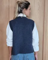 Chaleco de punto con diseño de trenzas, color gris oscuro, con cierre frontal de botones grandes y bolsillos laterales.