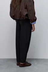 Pantalón marrón de tiro alto y silueta amplia, confeccionado con pinzas en el frente y bolsillos laterales.