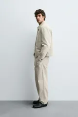 Sobrecamisa de corte regular confeccionada en tejido con estructura canvas color marrón. Presenta un ligero acolchado interior, cuello de solapa y cierre frontal con cremallera metálica. Incluye dos bolsillos de plastrón en el pecho y bolsillos laterales de vivo, con mangas largas terminadas en puños con botón.