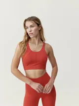 Top deportivo de sujeción media-alta, confeccionado en tejido técnico transpirable con perforaciones láser en la espalda.