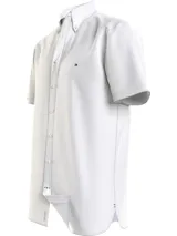 Camisa blanca de manga corta confeccionada en popelín de puro algodón, con cuello abotonado, corte regular y logo de Tommy Hilfiger bordado en el pecho.