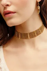 Gargantilla choker rígida de metal dorado con diseño texturizado de eslabones y cuentas en relieve.