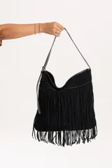 Cartera de hombro color negro, confeccionada en gamuza combinada con cuero sintético. Presenta un diseño con doble capa de flecos largos en la parte frontal y correa ajustable.