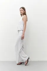 Pantalón blanco de lino, de corte ancho y con tajo lateral en el ruedo.