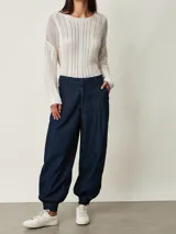 Pantalón slouchy de denim azul oscuro con pinzas en la cintura, bolsillos laterales y puños fruncidos con elástico en los tobillos.