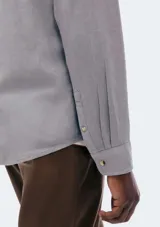 Camisa de manga larga en color gris, con cuello clásico, cierre frontal de botones y un bolsillo en el pecho.