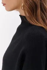 Polera de tejido de punto en color beige, con cuello alto y mangas largas con puños acanalados.