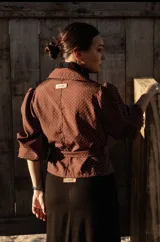 Camisa blanca con lunares celestes, de corte clásico, con cuello camisero y mangas largas abullonadas.