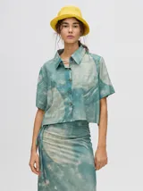 Camisa crop de manga corta con cuello camisero y cierre frontal de botones. Confeccionada en viscosa con un estampado abstracto único en tonos marrones y rosados.