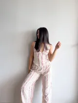 Conjunto de dos piezas compuesto por un top halter con escote en V y un pantalón de corte holgado con cintura elástica. Ambas prendas presentan un estampado de rayas verticales irregulares en tonos rosados sobre base cruda.