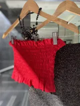 Top color crudo, sin mangas, con frunces en el busto y volados en el ruedo.