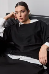 Sweater de punto liviano negro, con escote bote y mangas amplias de largo tres cuartos que aportan una silueta relajada y fluida.