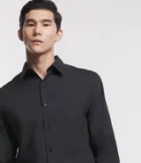 Camisa de corte regular confeccionada en microfibra, con cuello inglés, manga larga y cierre frontal abotonado. Presenta un diseño liso y minimalista, ideal para un estilo formal o de oficina.