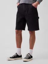 Bermuda de jean estilo carpenter color negro desgastado, de corte holgado, con bolsillos laterales utilitarios y presillas para martillo.