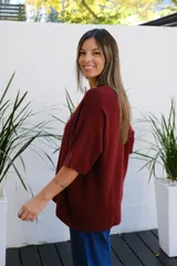 Sweater de punto color bordó, con cuello redondo, manga corta amplia y diseño holgado.