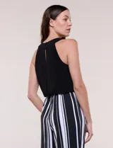 Enterito largo sin mangas con cuerpo negro de escote alto y pantalón wide leg de rayas verticales blancas y negras, con cintura elastizada y cordón ajustable.