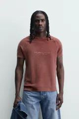 Remera de punto de algodón con efecto lavado, corte relajado, cuello redondo y mangas ranglán cortas. Presenta estampados a contraste en la parte delantera.