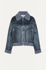 Chaqueta corta azul con efecto desgastado y cuello de piel sintética. Cuenta con cierre frontal con cremallera, dos bolsillos laterales con cremallera y puños y bajo con ribete de piel sintética.