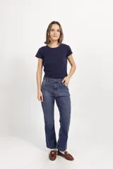 Jean de corte recto y tiro medio, confeccionado en denim azul clásico. Presenta diseño de cinco bolsillos con costuras reforzadas y cierre frontal con botón metálico.