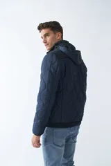 Campera de nylon azul marino para hombre con capucha, cierre frontal con cremallera, bolsillos laterales y frontales. El modelo usa talle M.