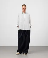 Camisa de algodón orgánico, blanca con finas rayas verticales negras. Presenta un corte oversize, cuello solapa, manga larga con puño y bolsillo en el pecho.
