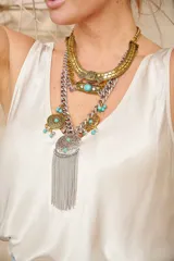 Collar estilo egipcio multicapa en tonos dorados y plateados, adornado con piedras turquesas y detalles colgantes de flecos de cadenas.