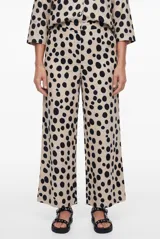 Pantalon tipo palazzo color negro con estampado paisley en tonos beige y blanco, corte holgado y tiro medio.