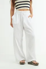 Pantalón blanco de gasa, de corte amplio y tiro alto, con cintura elástica y cordón ajustable.