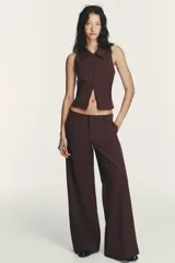 Chaleco de cuello solapa y manga sisa, color marrón con rayas verticales. Presenta cierre frontal con cremallera de doble cursor.