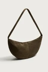 Bolso de hombro con diseño de media luna, confeccionado en piel con acabado de serraje. Cuenta con un asa integrada y cierre principal mediante cremallera.