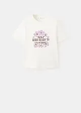 Remera de algodón color crudo, con cuello redondo, manga corta y estampa frontal de flores en tonos lilas con la leyenda "Self made ready to flourish".