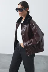 Campera de cuero sintético con acabado satinado, silueta relajada y elástico en la cintura. Presenta cuello con textura de piel sintética, cierre frontal y bolsillos laterales.