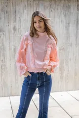 Blusa de cuello alto color rosado, de manga larga con elástico en el bajo y detalles de volados en la parte delantera.