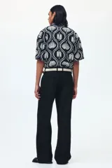 Pantalón sastrero de sarga en color negro, con corte holgado, piernas amplias con raya marcada, cierre frontal con botón y corchete ocultos, bolsillos al bies y bolsillos traseros insertados.