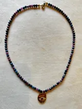 Collar de cuentas facetadas de piedras naturales multicolor con dije dorado ovalado en forma de sol con una piedra central.