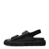Sandalias de plataforma plana Miss Carol Milan, color negro, con dos tiras anchas en el empeine provistas de grandes hebillas metálicas doradas y tira ajustable en el talón.