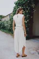 Pantalón fluido de tiro alto en color blanco, con pinzas delanteras, cintura elástica en la espalda y perneras anchas con aberturas laterales pronunciadas.