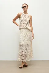 Top halter color beige claro, sin mangas, confeccionado en tejido de crochet con diseño de motivos geométricos y florales calados.
